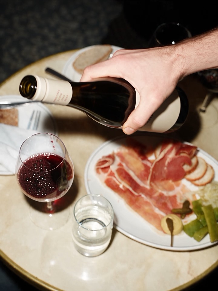 A glass of Sometimes Wine being poured at a shared table